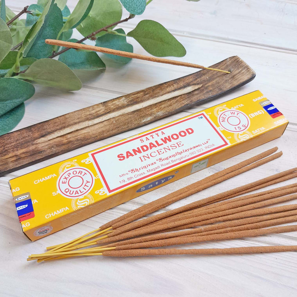 Packet of sandalwood incense sticks next to a plant.